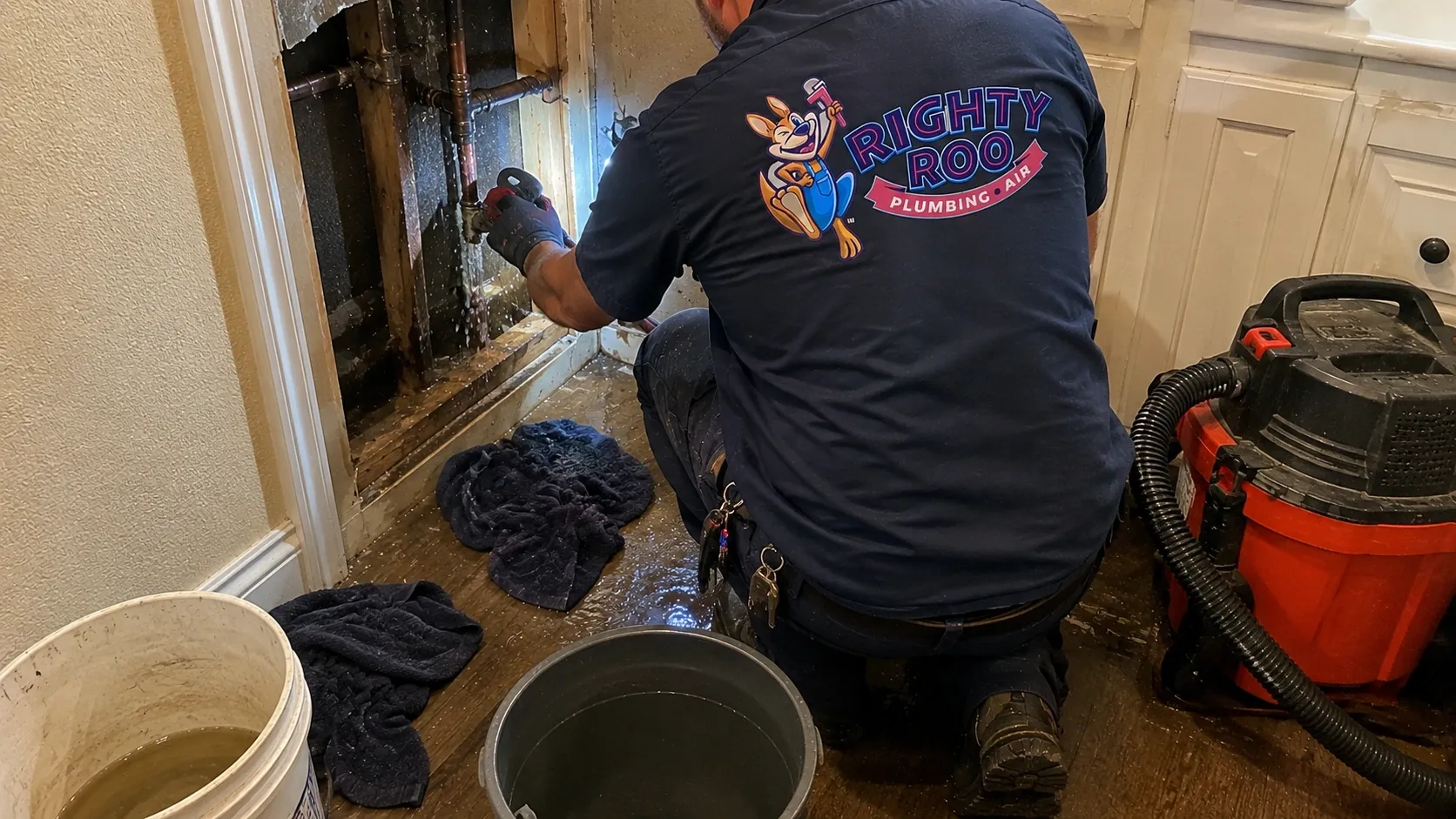 A Righty Roo plumber fixing leaking pipes inside a wall